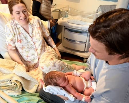 New mother smiling with partner and newborn baby